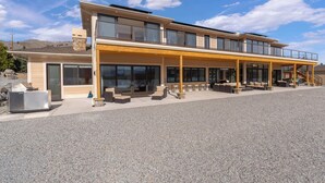 A modern two-story building with a covered patio area, large windows, and a stone chimney. - Private beach with panoramic lake views (Entiat)