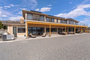 A modern two-story building with a covered patio area, large windows, and a stone chimney. - Private beach with panoramic lake views (Entiat)