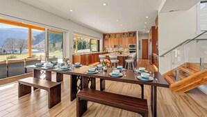 A modern kitchen with wooden cabinets, a central island, and a dining area with a long table set for six. - Private beach with panoramic lake views (Entiat)