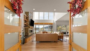 A modern interior with a central seating area, a stone accent wall, and a large window offering a view of the outdoors. - Private beach with panoramic lake views (Entiat)