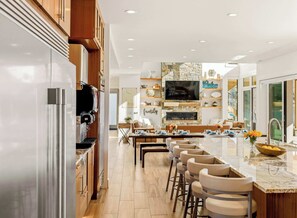 Une cuisine moderne dotée d’un îlot central, de tabourets de bar et d’un coin repas avec une table dressée pour quatre personnes.