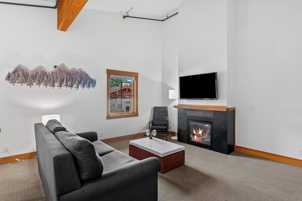 A modern living room with a fireplace, a flat-screen TV, a sofa, and a coffee table.