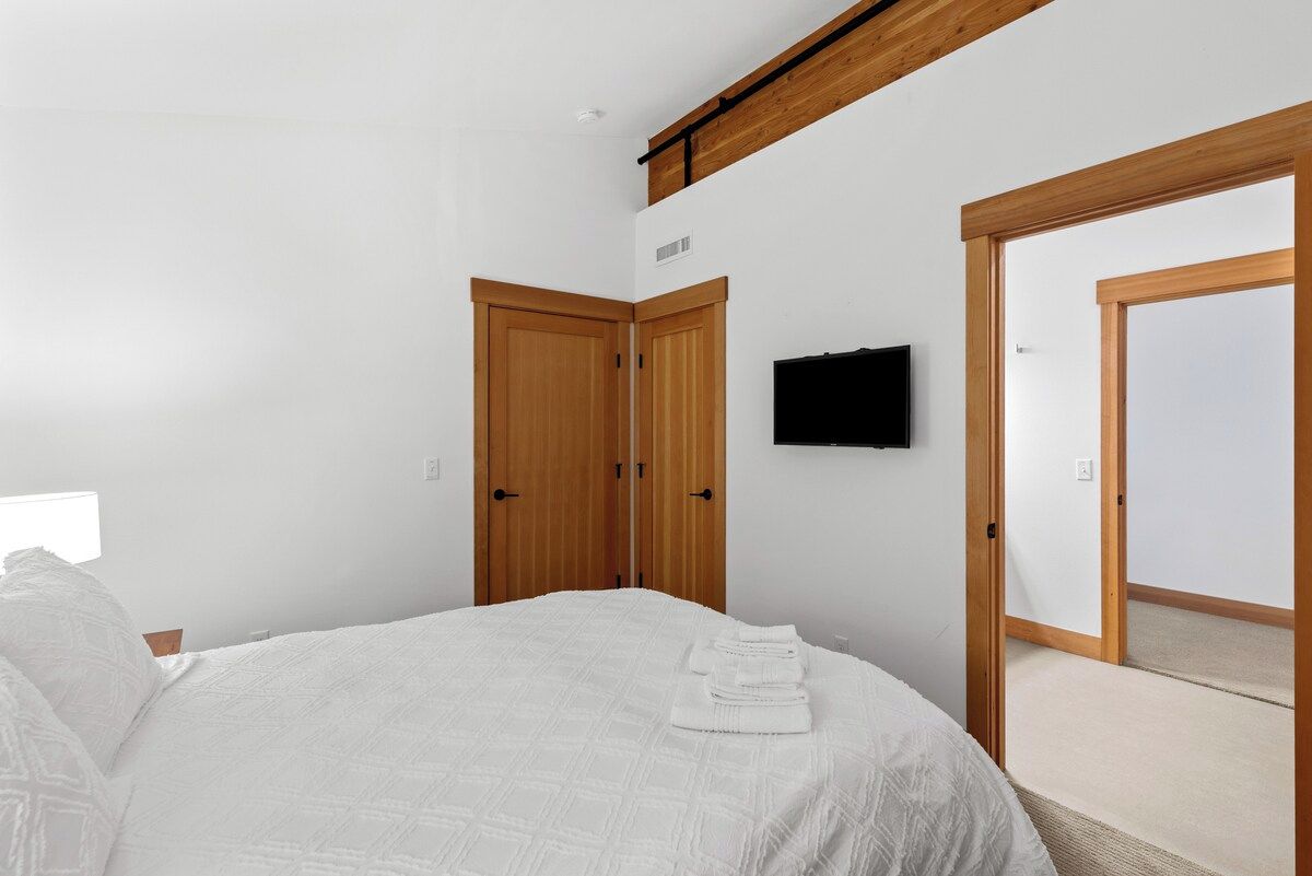Una camera da letto con un letto, una TV a parete e porte in legno.