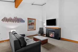 A modern living room with a fireplace, a flat-screen TV, a sofa, and a coffee table. - As twilight descends over the Cascade Mountains, your private balcony at Front S (Leavenworth)