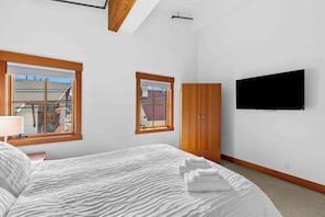 A bedroom with a bed, a TV, and a window. - As twilight descends over the Cascade Mountains, your private balcony at Front S (Leavenworth)