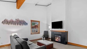 Ein modernes Wohnzimmer mit einer Couch, einem Couchtisch, einem Kamin und einem an der Wand befestigten Fernseher.