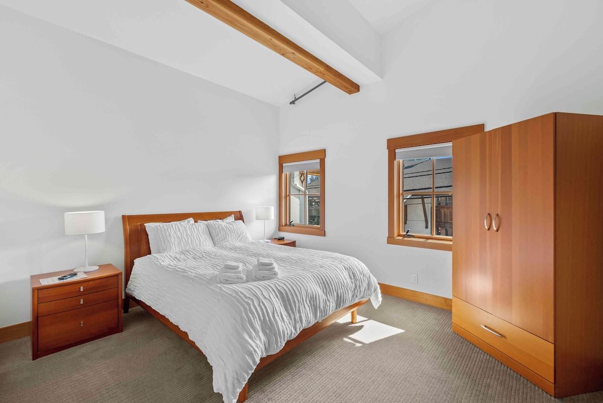 A bedroom with a wooden bed, a nightstand, a wardrobe, and a window with a view.