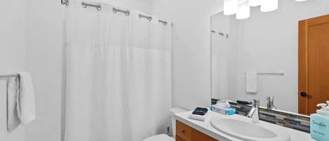 A modern bathroom with a white toilet, a shower curtain, a vanity with a sink, a mirror, and a towel rack.