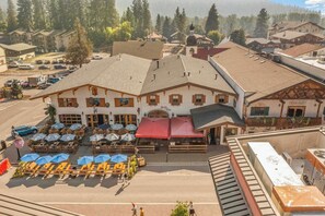 A hotel with outdoor seating and a red awning. - As twilight descends over the Cascade Mountains, your private balcony at Front S (Leavenworth)