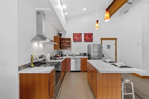 A modern kitchen with a central island, stainless steel appliances, wooden cabinets, and pendant lighting. - As twilight descends over the Cascade Mountains, your private balcony at Front S (Leavenworth)
