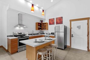 A modern kitchen with a central island, stainless steel appliances, wooden cabinets, and pendant lighting. - As twilight descends over the Cascade Mountains, your private balcony at Front S (Leavenworth)