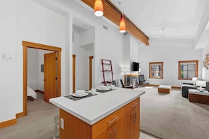 A spacious living area with a large island, wooden beams, and a television. - As twilight descends over the Cascade Mountains, your private balcony at Front S (Leavenworth)