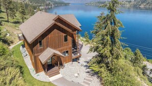 Eine Holzhütte mit Balkon, gelegen am See mit Bergen im Hintergrund.