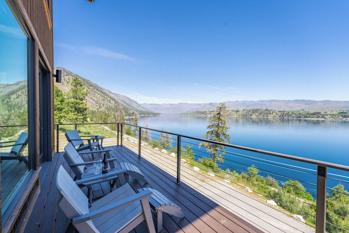 Une terrasse avec des sièges extérieurs, offrant une vue sur un lac et des montagnes.