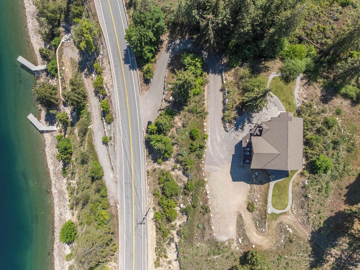 An aerial view of a coastal property with a road, a small house, and a dock.