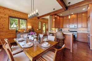 A wooden interior with a dining area, kitchen, and large windows.