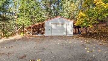 A single-story building with a garage, surrounded by trees and a gravel driveway.