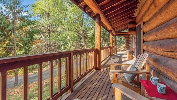 Eine Holzterrasse mit Geländer, Holzstühlen und einer Bank.