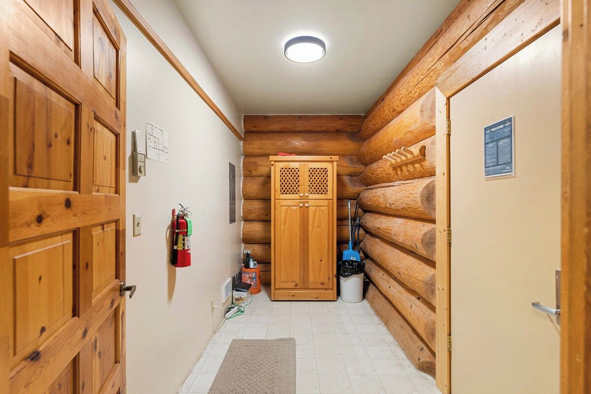 A welcoming hallway connects you to different areas of this charming log home, featuring warm natural wood accents and modern tiled flooring.