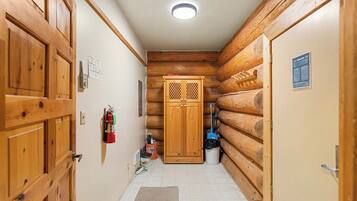 A welcoming hallway connects you to different areas of this charming log home, featuring warm natural wood accents and modern tiled flooring.