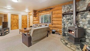 Ein Blockhaus-Interieur mit Kamin aus Stein, Holzwänden und einer gemütlichen Sitzecke.