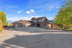 A two-story house with a garage, driveway, and a view of mountains in the background. - As the Chelan Valley sky transitions into twilight, take your place in the steam (Manson)