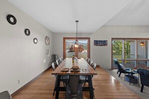 A dining area with a long wooden table, multiple chairs, and a hanging light fixture. - As the Chelan Valley sky transitions into twilight, take your place in the steam (Manson)