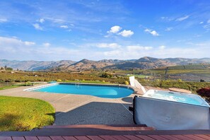 A swimming pool with a hot tub and a deck area, surrounded by a mountainous landscape. - As the Chelan Valley sky transitions into twilight, take your place in the steam (Manson)