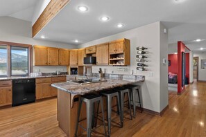 A modern kitchen with wooden cabinets, a granite countertop, and a built-in wine rack. - As the Chelan Valley sky transitions into twilight, take your place in the steam (Manson)