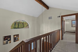A hallway with a wooden railing, a large window with a view of trees, and a door leading to another room. - As the Chelan Valley sky transitions into twilight, take your place in the steam (Manson)