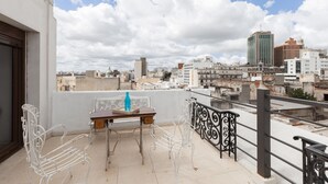 Ein Balkon mit Tisch und Stühlen mit Blick auf eine Stadtlandschaft und verschiedenen Gebäuden.
