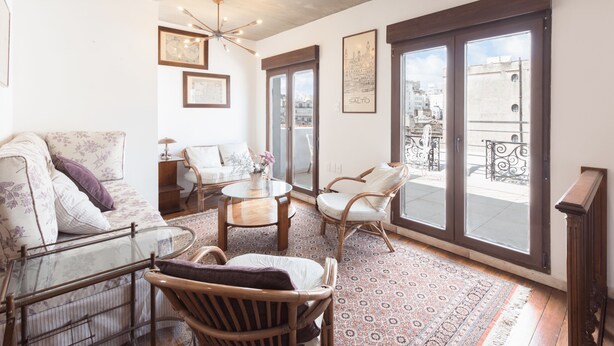 Ein Wohnzimmer mit Sofa, Sesseln, einem Couchtisch und einem großen Fenster mit Blick auf die Stadt.
