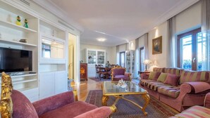 Een ruime woonkamer met een televisie, comfortabele zithoek en een eethoek.