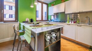 Een moderne keuken met een centraal eiland, witte kasten en een groene accentmuur.