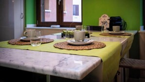 Een eethoek met een tafel gedekt voor twee personen, voorzien van geweven placemats, borden en glazen.