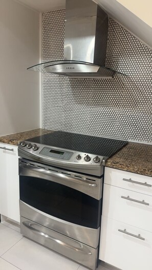 A stainless steel kitchen with a gas stove, oven, and a glass range hood.