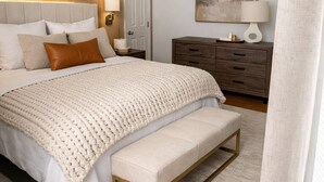 Ein Schlafzimmer mit einem großen Bett, einer Bank, einer Kommode und einem Bild an der Wand.