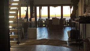 Ampla sala de estar com uma grande janela com vista panorâmica, escada com iluminação embutida e design de interiores moderno.