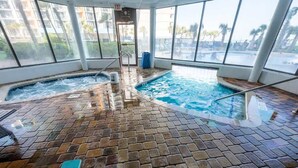 En inomhuspool med två separata avdelningar, ett tegelgolv och stora fönster som ger utsikt över omgivningen.