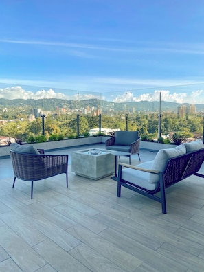 A rooftop patio with outdoor furniture, a fire pit, and a city view. - Modern Apt z:10+jacuzzi+laundry+AC+GYM@GTCity (Ciudad de Guatemala)