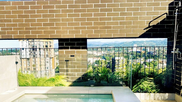 Une piscine sur le toit offrant une vue dégagée sur le paysage urbain et les montagnes en arrière-plan.