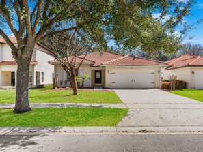 A residential house with a red-tiled roof, a garage, and a well-maintained lawn. - 4Br Single Level, Pool Near Disney (Kissimmee)