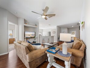 A living room with two sofas, a coffee table, a TV, and a ceiling fan. - 4Br Single Level, Pool Near Disney (Kissimmee)