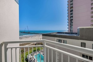 A balcony with a view of the beach, a pier, and a pool. - Oceanview 1BR at Carolinian, Pools, Great Location (Myrtle Beach)