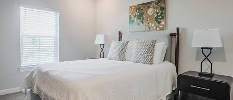 Une chambre à coucher avec un lit, deux lampes de chevet, un tableau et un radiateur encastré.