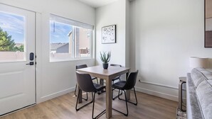 Ein modernes Wohnzimmer mit Esstisch, Stühlen, einer Couch und einem Blumentopf.