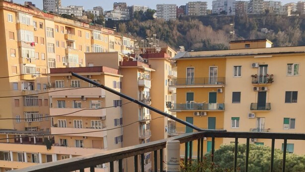 A balcony with a table, two wine glasses, a bottle of wine, and a potted plant. - Augusto 42 apartment Napoli.  Stadium Metro & Free Parking (Napoli)