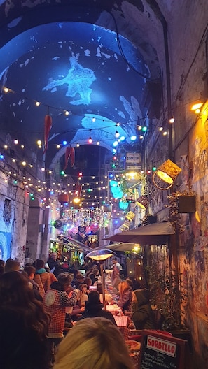 Ein Essbereich mit Tischen, Stühlen und hängenden Lampen.