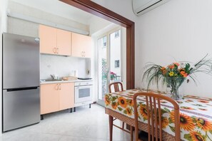 Eine kleine Küche mit einem Edelstahlkühlschrank, pfirsichfarbenen Schränken und einem Esstisch mit Sonnenblumen Tischdecke.