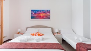 A hotel room with a large bed, two bedside tables, a small sofa, and a painting of a sunset on the wall. - Augusto 42 apartment Napoli.  Stadium Metro & Free Parking (Napoli)